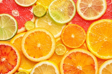 Photo of Slices of fresh citrus fruits as background, top view