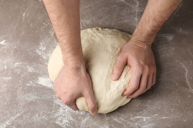 Male baker preparing bread dough at grey table, top view