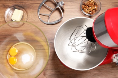 Red stand mixer and different ingredients on wooden table, flat lay