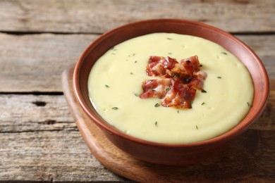 Photo of Tasty potato soup with bacon and rosemary in bowl on wooden table, closeup