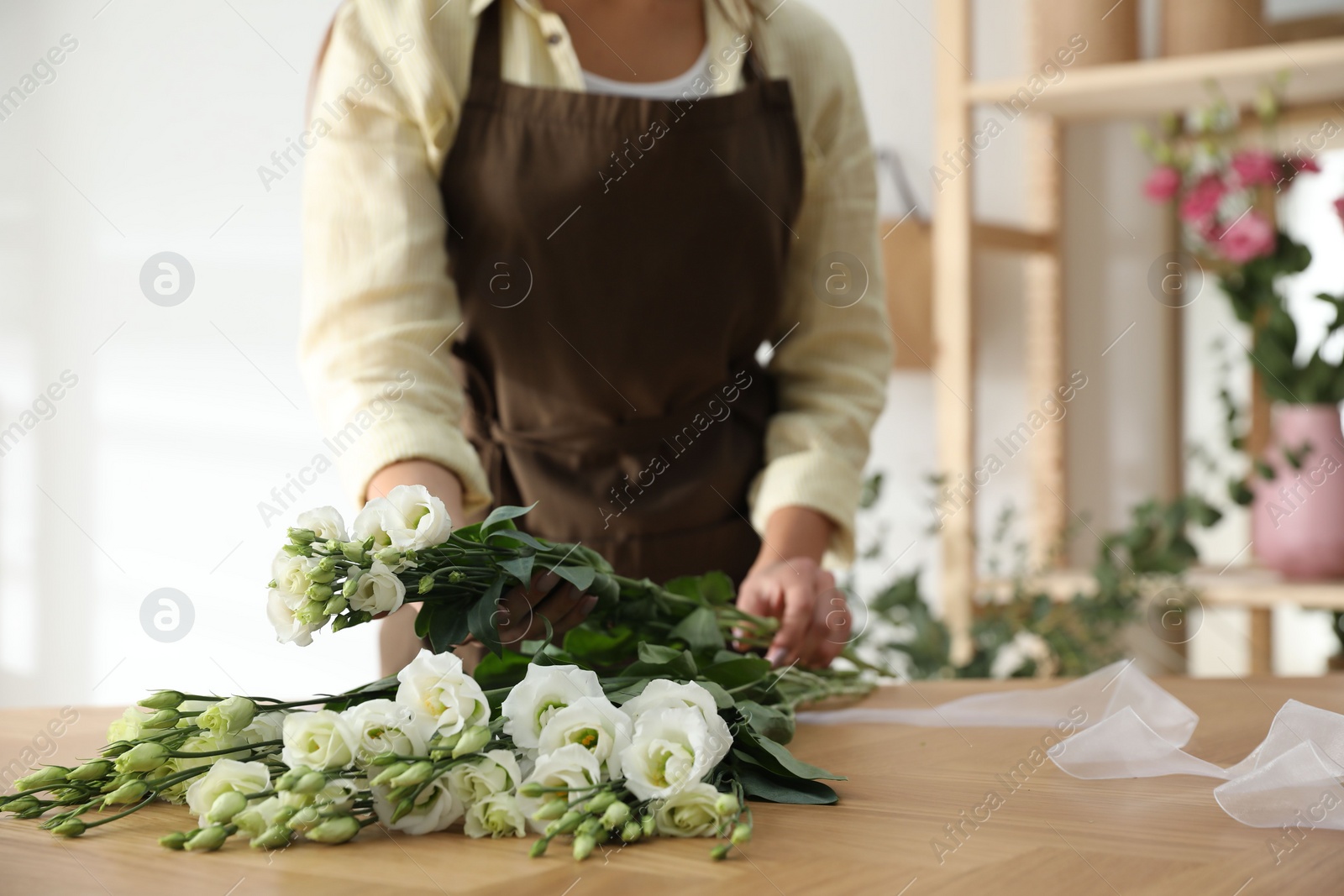 Photo of Florist making beautiful bouquet at table in workshop, closeup