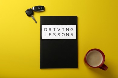 Photo of Flat lay composition with workbook for driving lessons on yellow background. Passing license exam