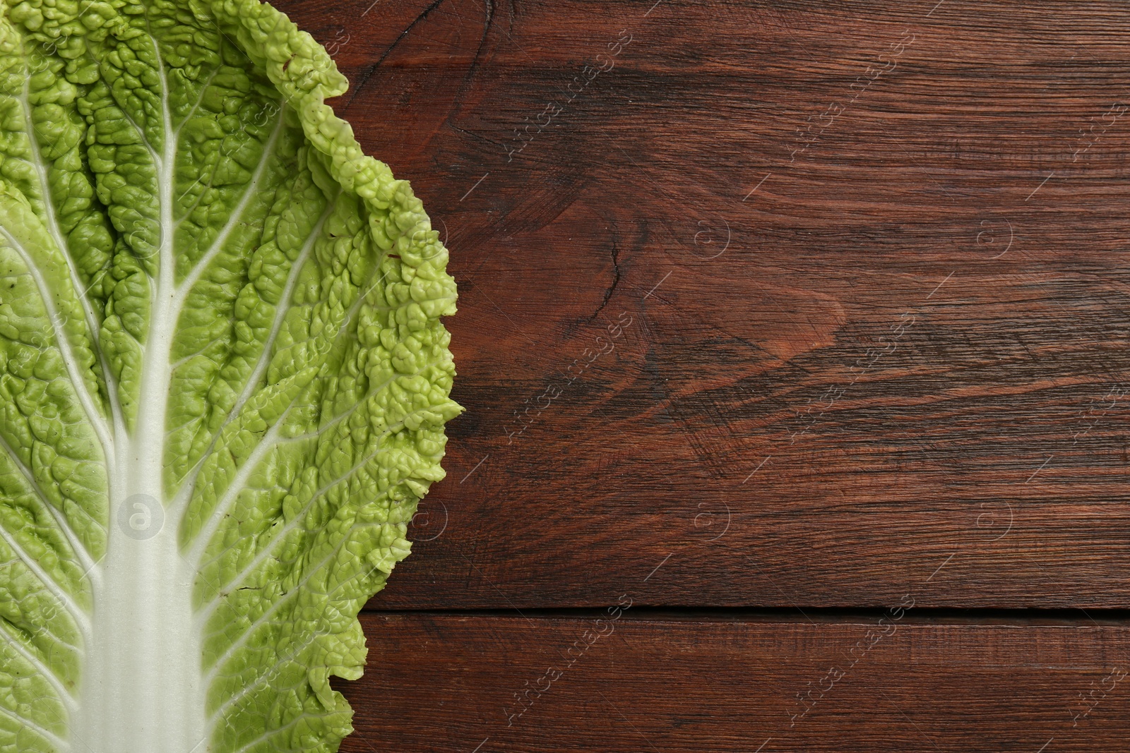 Photo of Fresh leaf of Chinese cabbage on wooden table, top view. Space for text