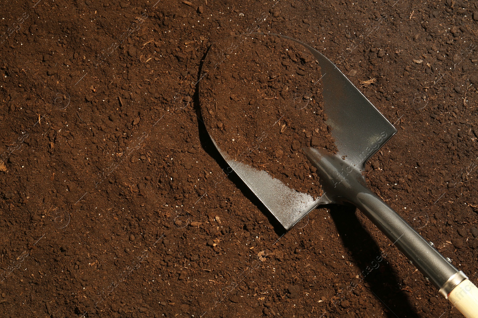 Metal shovel on fertile soil, top view and space for text. Gardening tool Photo of Metal shovel on fertile soil, top view and space for text. Gardening tool