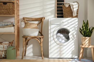 Photo of Modern washing machine in laundry room interior