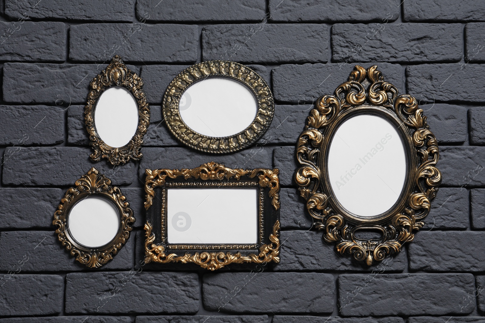 Photo of Empty vintage frames hanging on dark brick wall. Mockup for design