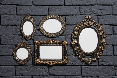 Photo of Empty vintage frames hanging on dark brick wall. Mockup for design
