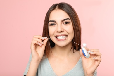 Photo of Young woman flossing teeth on color background