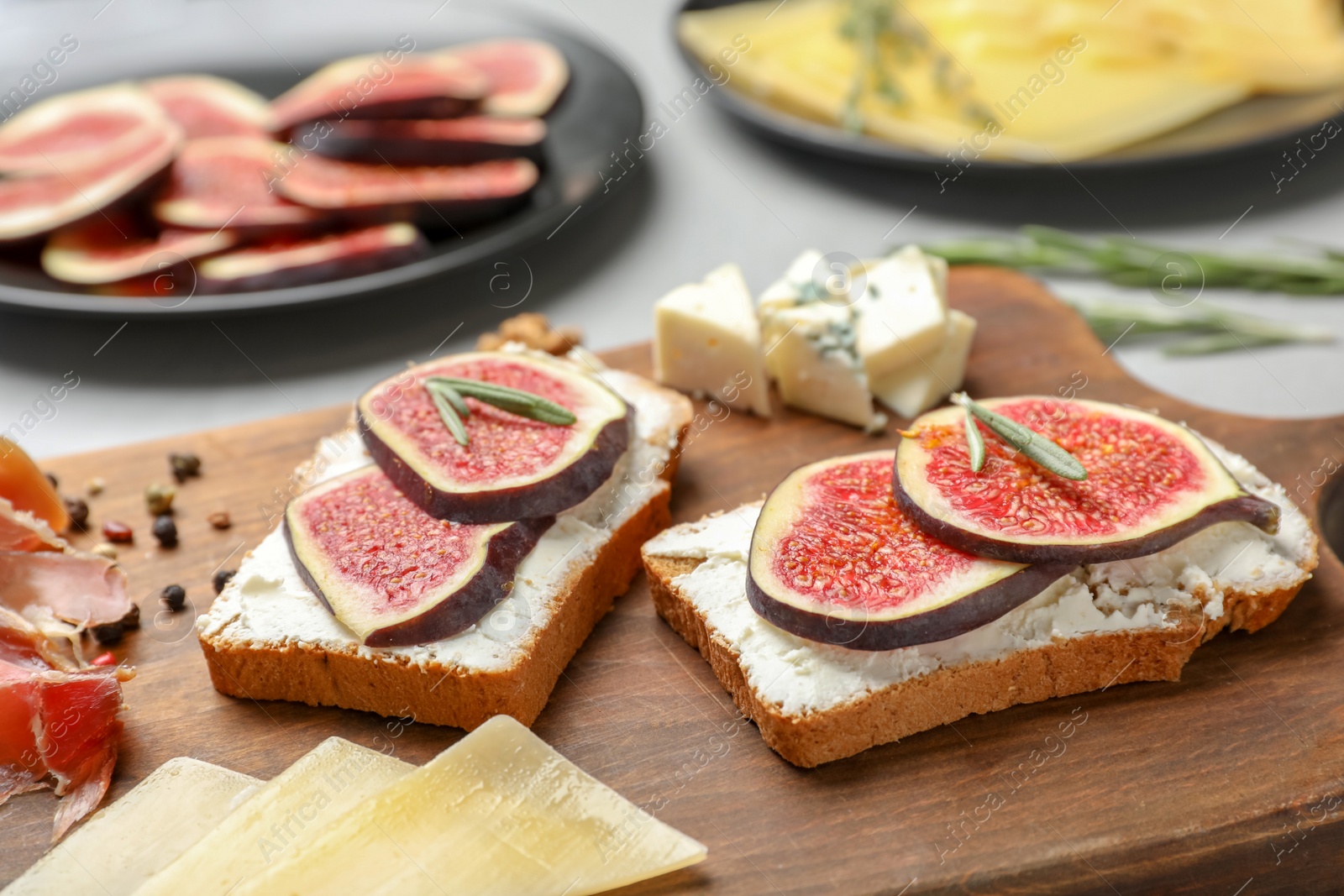 Photo of Sandwiches with ripe figs and cream cheese on wooden board