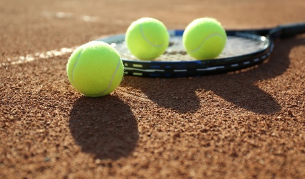 Tennis balls and racket on clay court