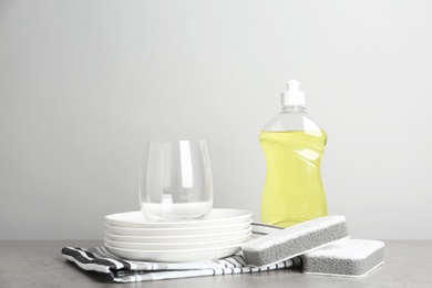 Photo of Cleaning supply and sponges for dish washing near plates on grey table