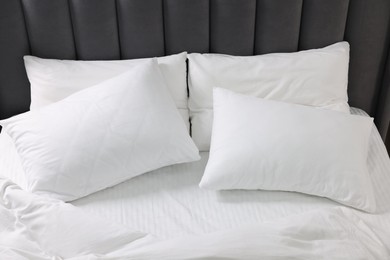 Photo of Soft white pillows and duvet on bed