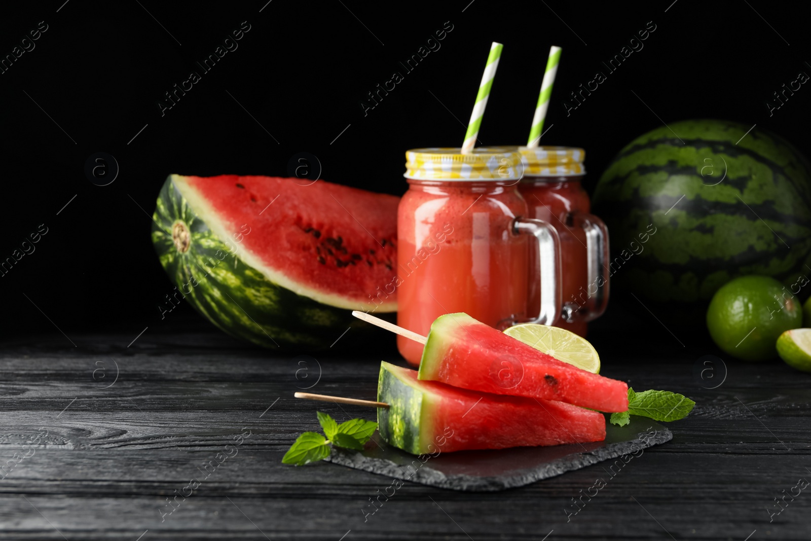 Photo of Slate board with juicy watermelon and lime on black wooden table, space for text