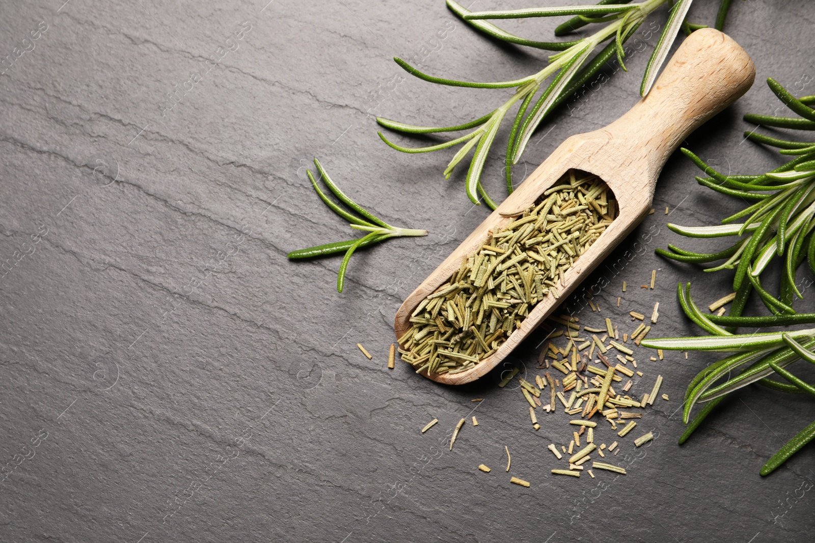Photo of Wooden scoop with dry and fresh rosemary on black table, flat lay. Space for text