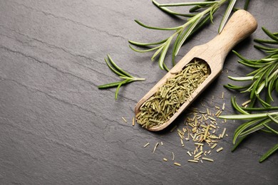 Wooden scoop with dry and fresh rosemary on black table, flat lay. Space for text