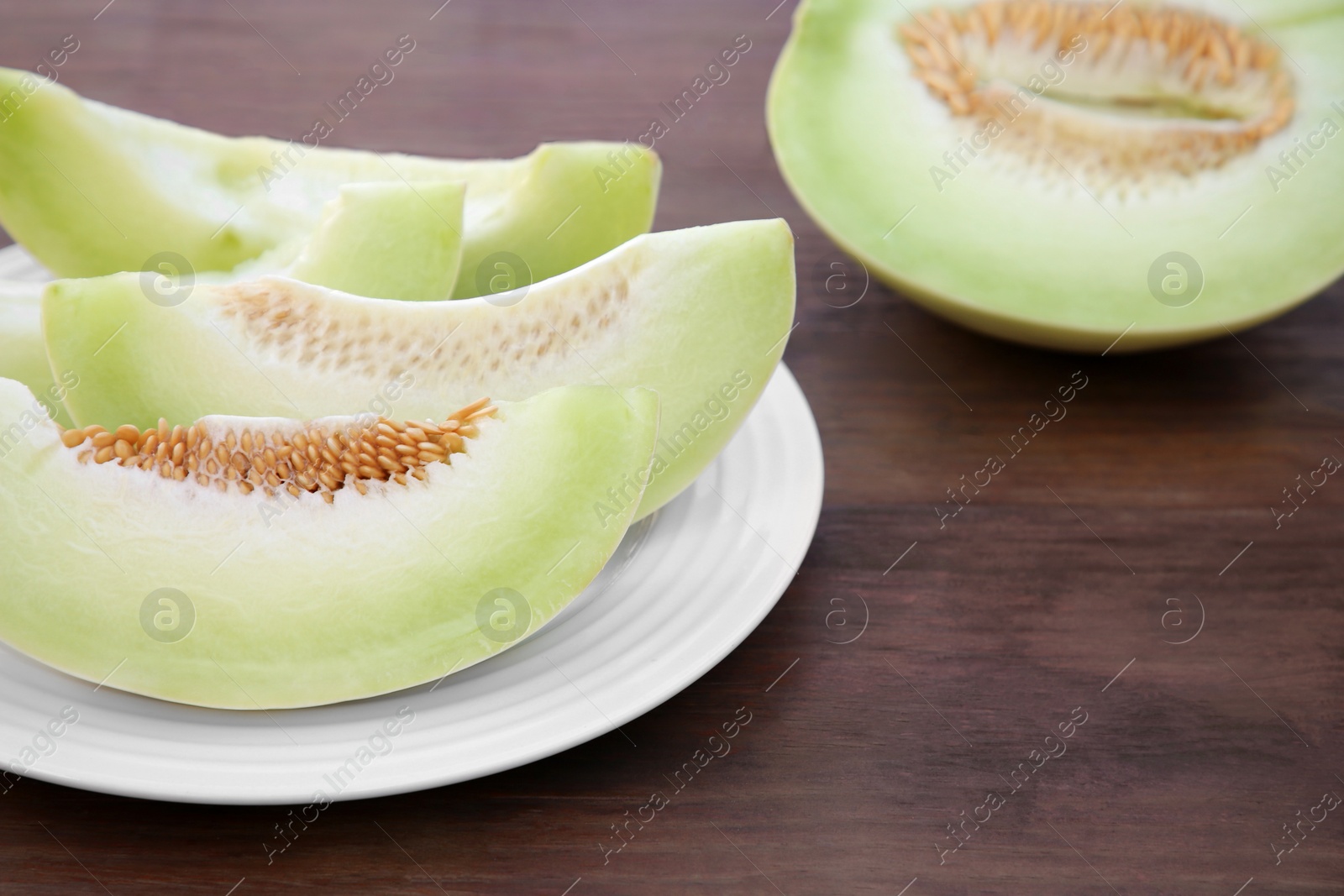 Photo of Cut tasty ripe melon on wooden table. Space for text