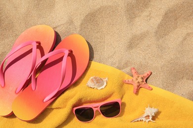 Photo of Flip flops and other beach items on sand, flat lay. Space for text