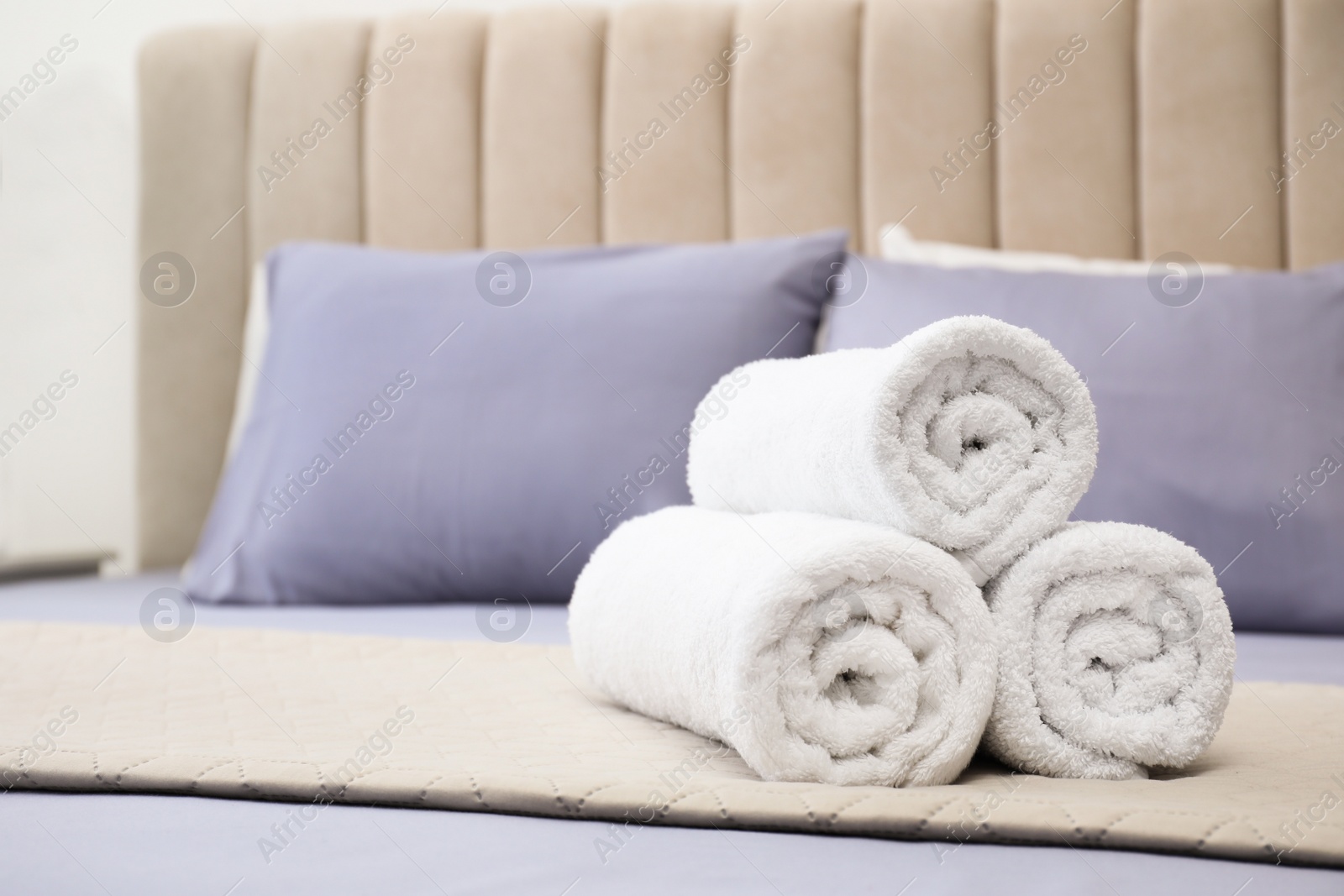 Photo of Rolled soft clean towels on bed indoors. Space for text