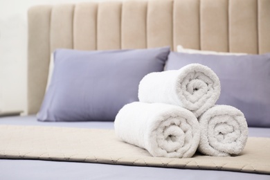 Rolled soft clean towels on bed indoors. Space for text