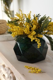 Beautiful mimosa flowers on chest of drawers indoors