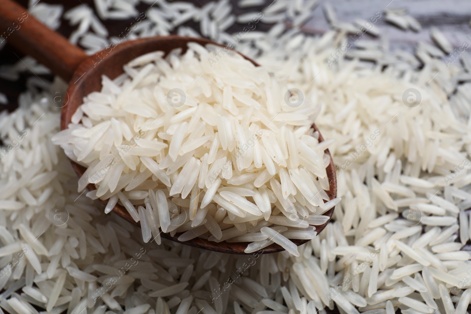 Photo of Raw basmati rice and wooden spoon on table, closeup