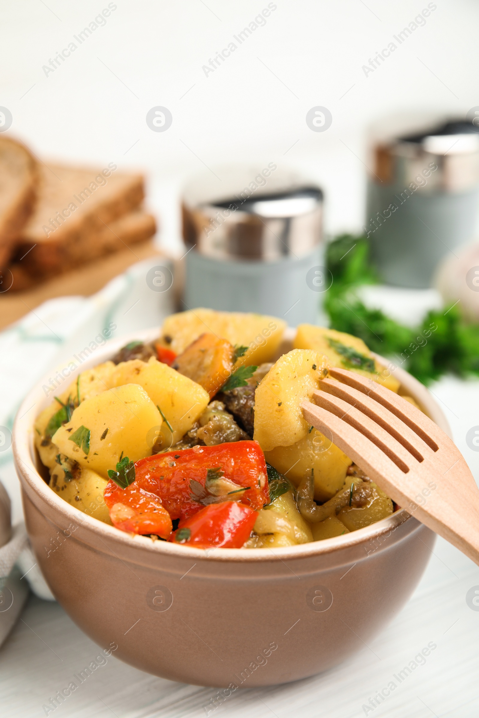 Photo of Tasty cooked dish with potatoes in earthenware served on white table