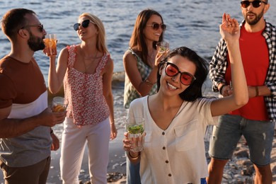 Woman with friends having fun near river at summer party