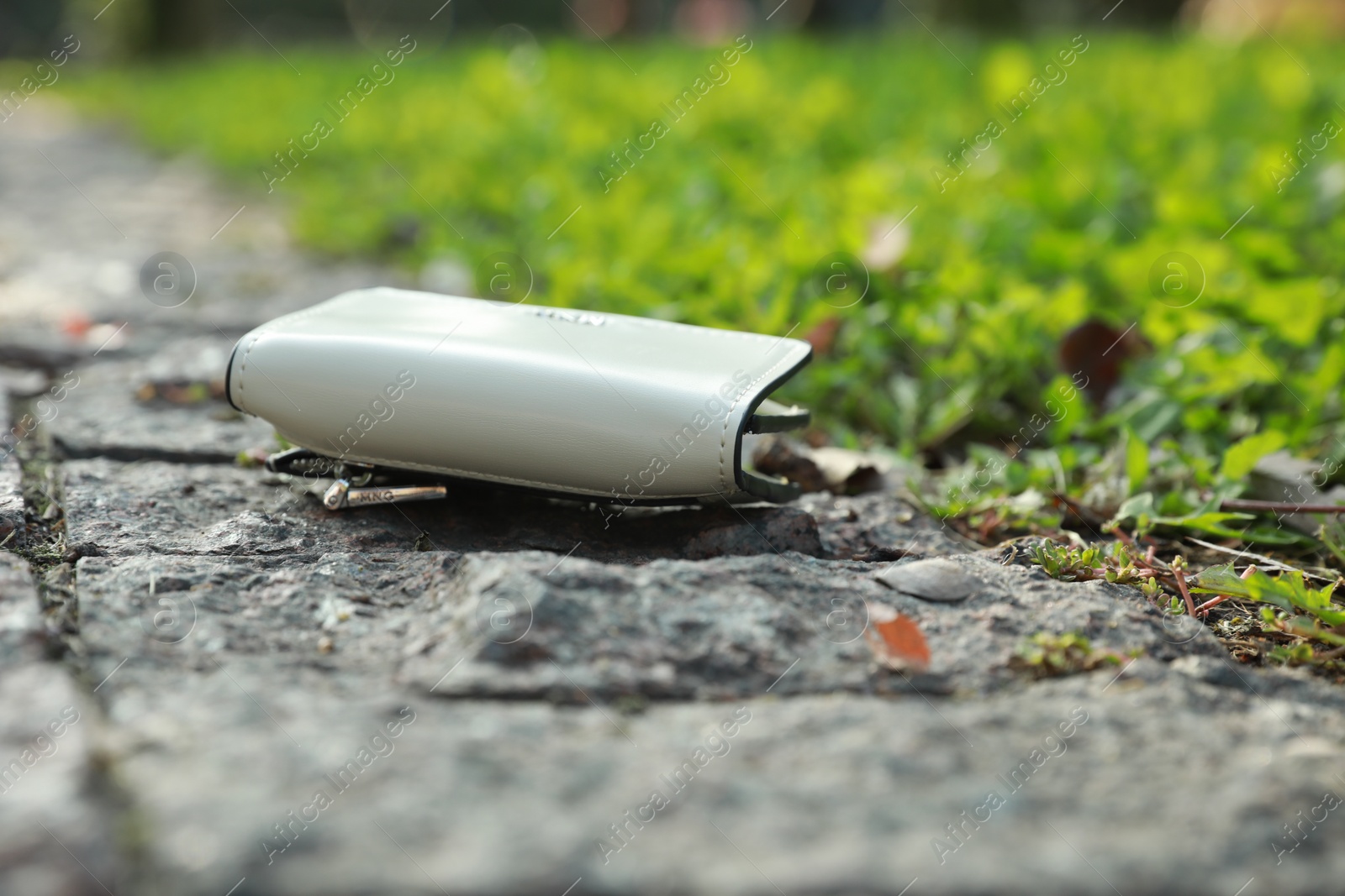 Photo of White leather purse on stone surface outdoors, closeup. Lost and found