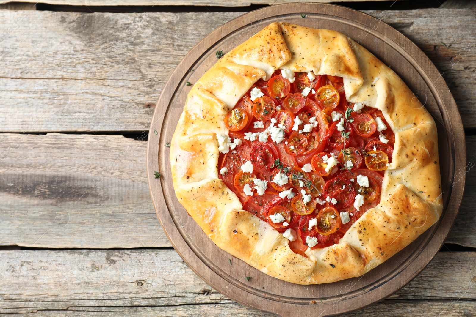 Photo of Tasty galette with tomato, thyme and cheese (Caprese galette) on wooden table, top view. Space for text