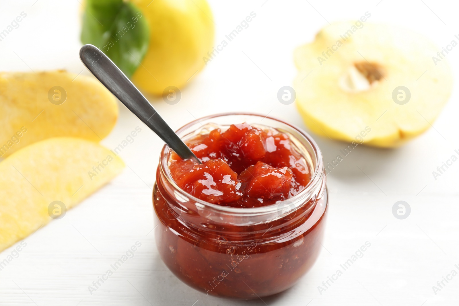 Photo of Delicious quince jam and fruits on white wooden table