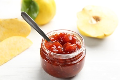 Photo of Delicious quince jam and fruits on white wooden table