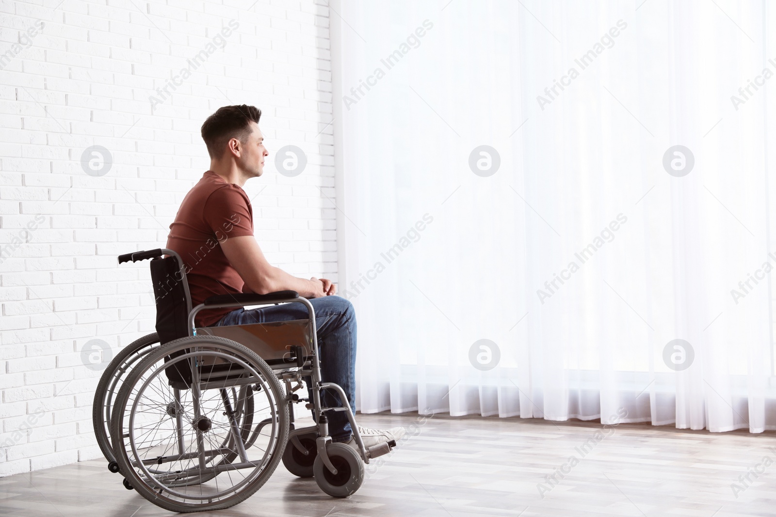 Photo of Thoughtful man sitting in wheelchair near window at home