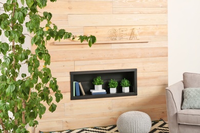 Photo of Stylish room interior with large houseplant near wooden wall