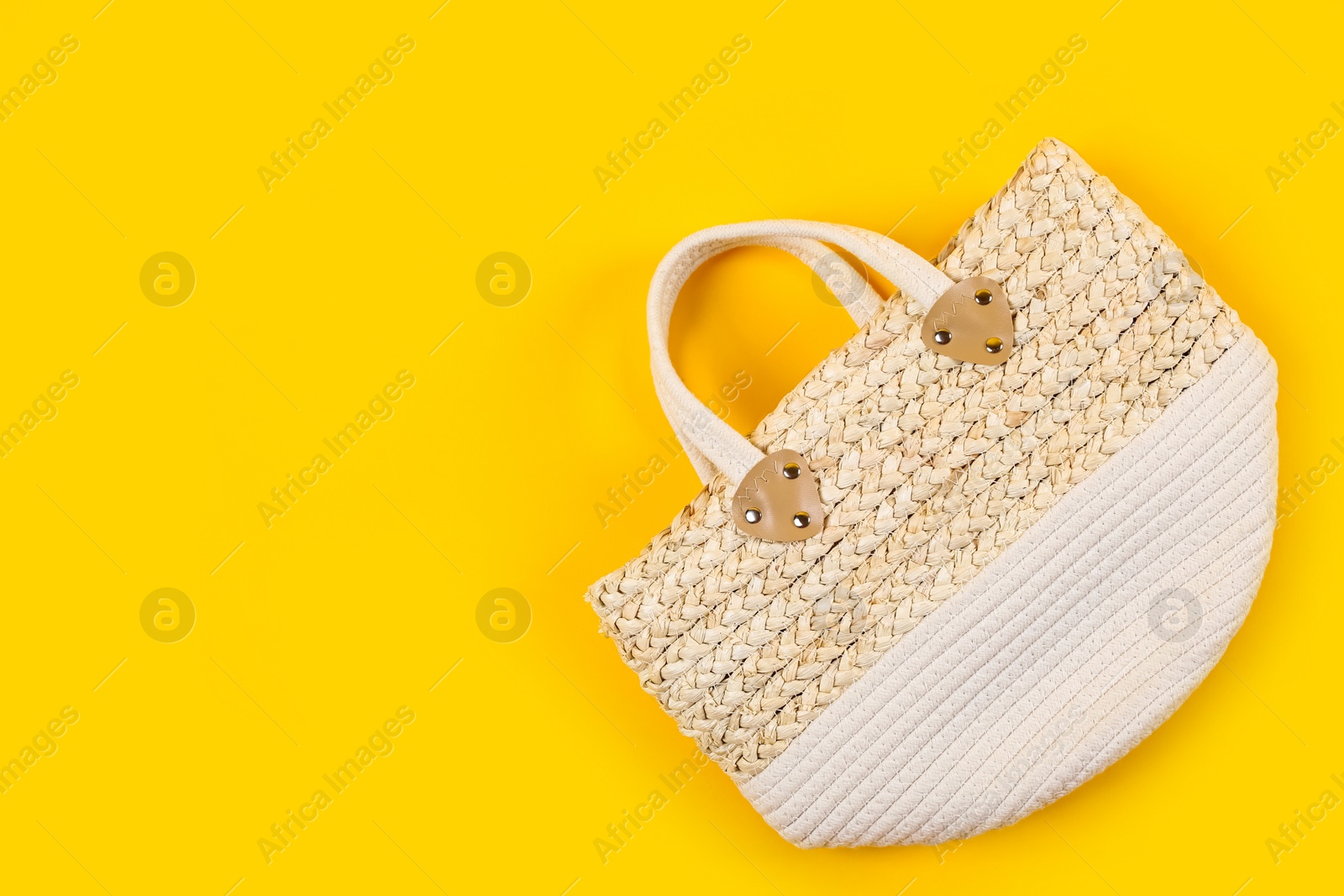 Photo of Stylish woman's straw bag on yellow background, top view. Space for text