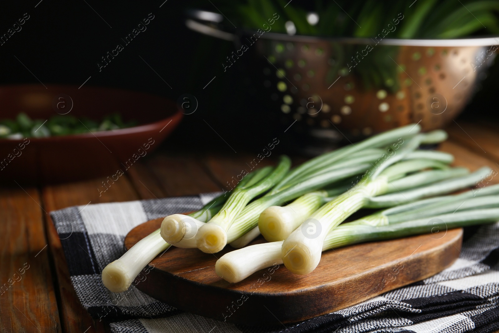 Photo of Fresh green spring onions on wooden board