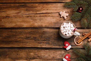 Flat lay composition of delicious hot chocolate with marshmallows and Christmas decor on wooden table, space for text