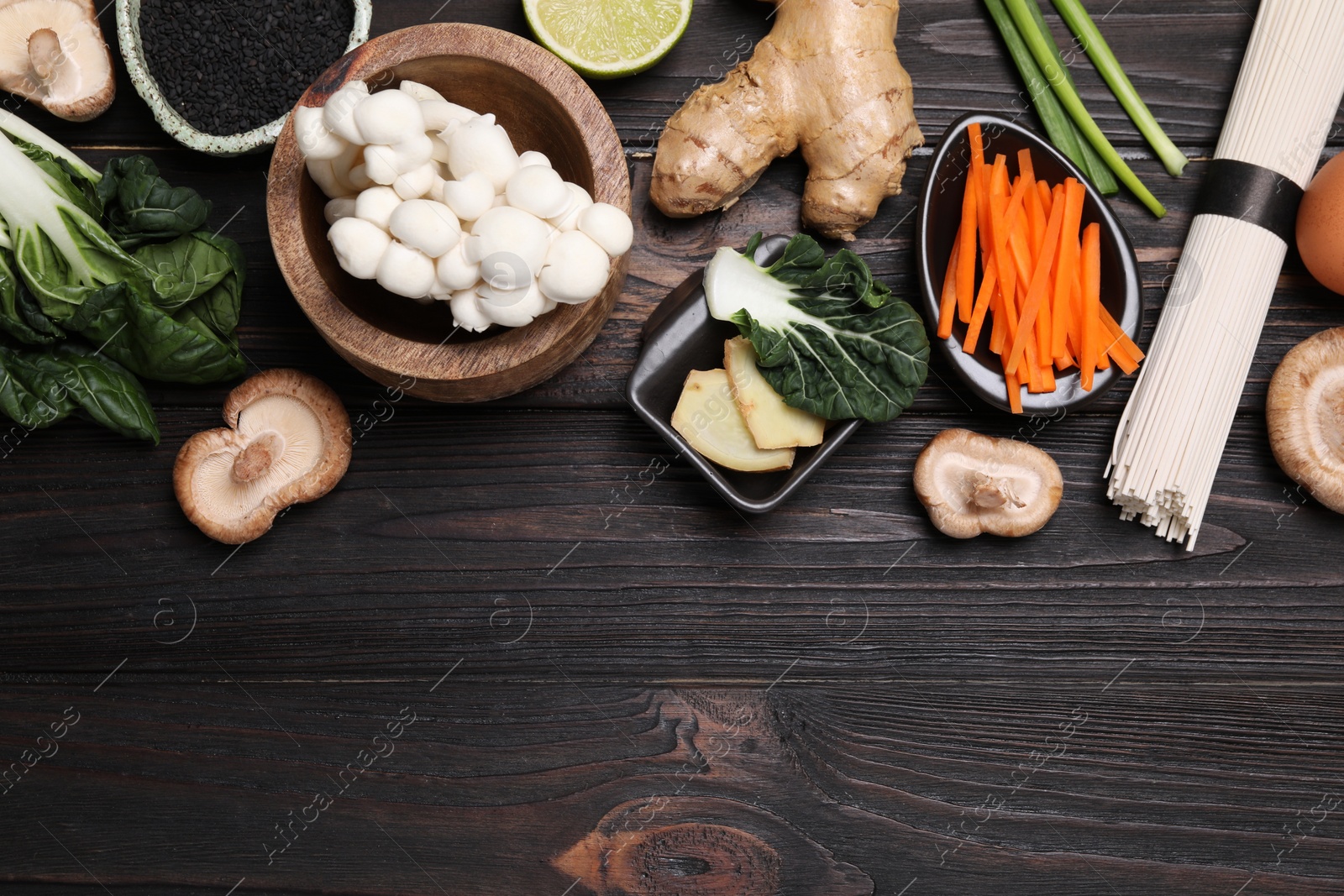 Photo of Cooking delicious ramen soup. Different ingredients on wooden table, flat lay. Space for text