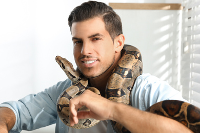 Photo of Man with his boa constrictor at home. Exotic pet