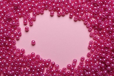 Photo of Frame of bright beads on pink background, flat lay. Space for text