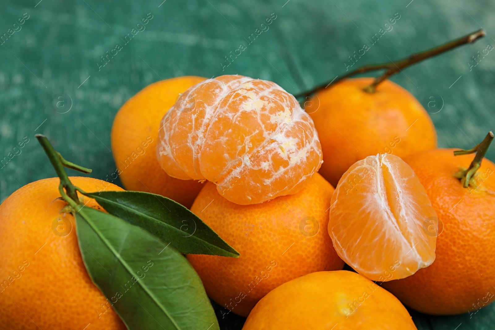 Photo of Fresh ripe tangerines with green leaves on table