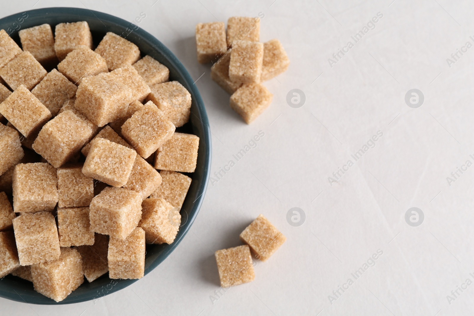 Photo of Brown sugar cubes on light table, flat lay. Space for text