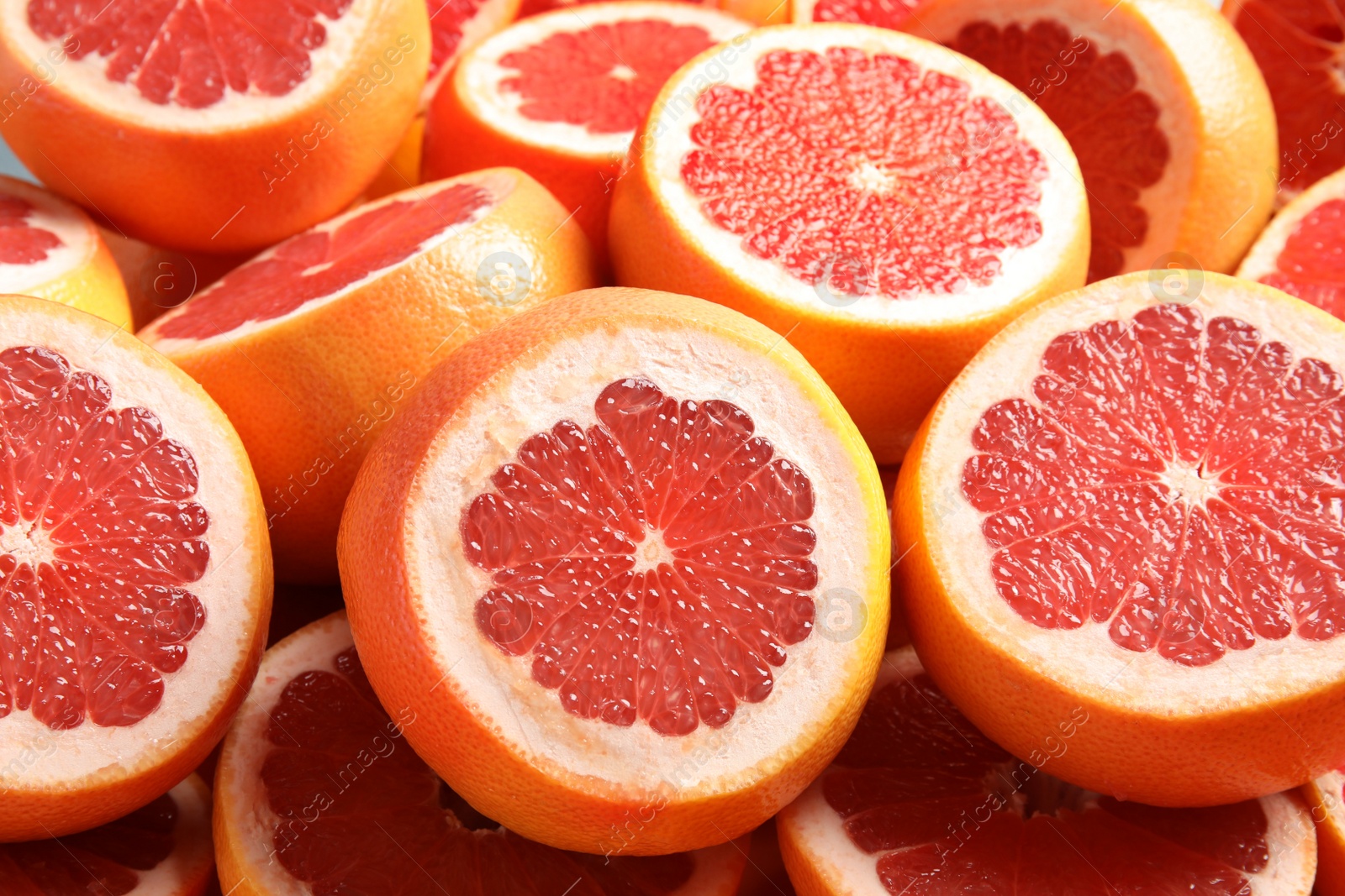 Photo of Many sliced fresh ripe grapefruits as background, closeup