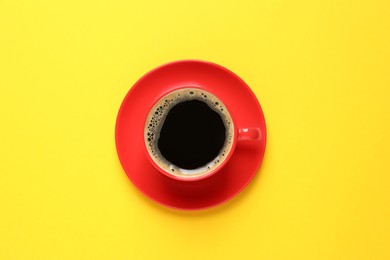 Photo of Aromatic coffee in red cup on yellow background, top view