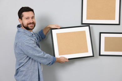 Man hanging picture frame on gray wall