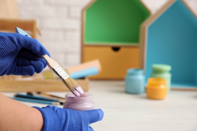 Photo of Decorator holding jar of violet paint and brush, closeup. Space for text