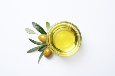 Little bowl with oil, ripe olives and leaves on white background