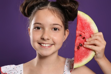 Cute little girl with watermelon on purple background