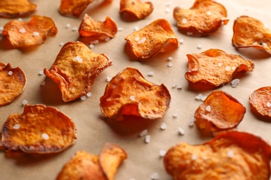 Photo of Sweet potato chips with salt on color background, closeup