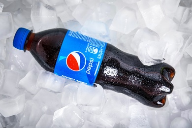 MYKOLAIV, UKRAINE - FEBRUARY 11, 2021: Plastic bottle of Pepsi on ice cubes, top view