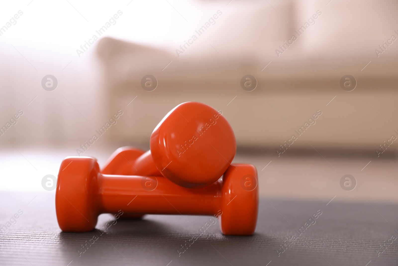 Photo of Orange dumbbells on floor in room. Home fitness